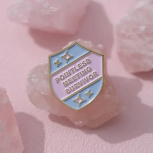 Cartoon shield enamel pin 'Pointless Meeting Survivor' badge in blue and pink pastel