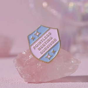 Pink shield-shaped enamel pin with Pointless Meeting Survivor text on natural pink stone