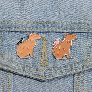 Cartoon capybara enamel pins on denim jacket featuring cute animals with small birds