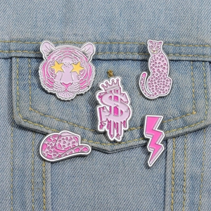 Detalle de broches de esmalte rosa con tigre y leopardo en una chaqueta vaquera azul claro