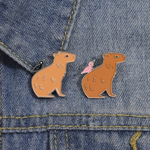 Set of two cute Capybara enamel pins attached to a blue denim jacket collar