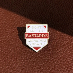 Shield enamel brooch with Don't Let The Bastards Grind You Down text on leather