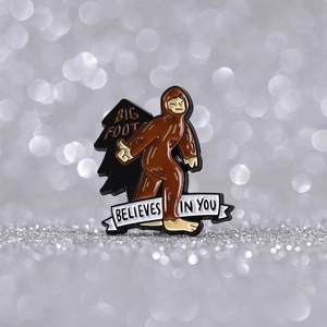 Detailaufnahme der Emaille-Anstecknadel Big Foot mit motivierendem Spruch auf Bokeh-Effekt