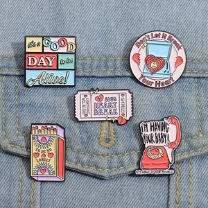 Close-up of retro pink enamel pins featuring jukebox and telephone on denim fabric