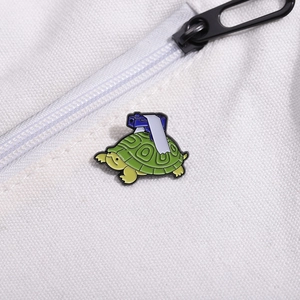 Macro shot of green turtle enamel pin with blue gun model detail on white canvas background