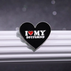 Close-up of heart enamel pin with I love my boyfriend text on white display stand