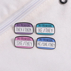 Set of four colorful pronoun enamel pins including THEY/THEM and HE/SHE pinned on a bag