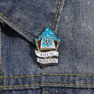 Épingle émaillée détaillée avec flamme bleue et dé d20 sur tissu en jean bleu