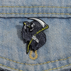 Detail of grim reaper enamel pin on denim jacket featuring scythe and drink design