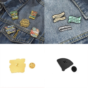 Detail of inspirational colorful enamel pins with English quotes on denim fabric back