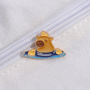 Detail view of cartoon capybara enamel pin with yellow ducks on a white canvas background