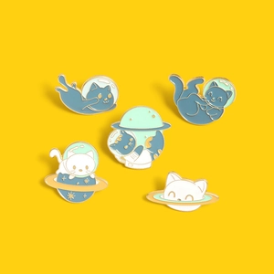 Detailed view of 5-piece enamel catstronaut pins with blue and gold metal finish