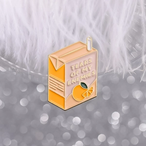 Orange milk carton enamel pin with Tears of My Enemies text and straw design