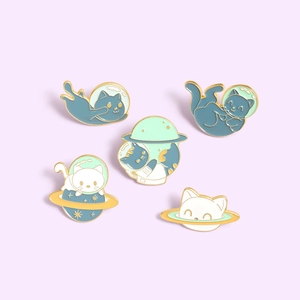 Macro view of space-themed cat enamel pins with blue and white cosmic designs