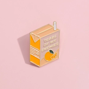 Pin's en émail boîte de jus d'orange avec texte humoristique sur fond rose pastel