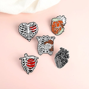 Détail de cinq broches en émail anatomiques avec motifs de cage thoracique et cœur
