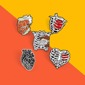 Vue détaillée de 5 broches en émail anatomique avec motifs de cœur et cage thoracique