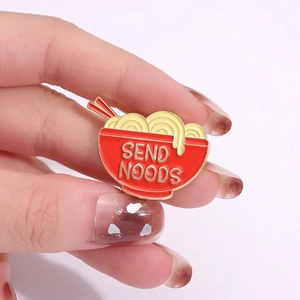 Cartoon ramen bowl enamel pin with Send Noods text and red chopsticks on pink background