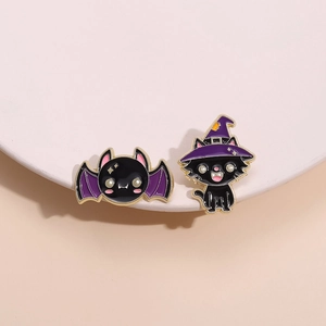 Halloween punk bat and black cat wizard enamel pins on white stand with warm background