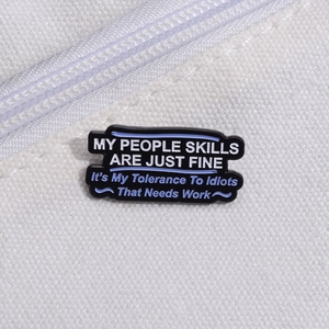 Detail of a rectangular black enamel brooch with quote on a canvas bag background