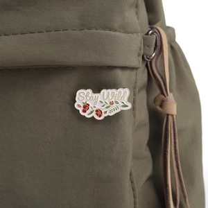 Cartoon white cloud enamel pin with Stay Wild text on a green canvas bag