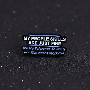 Funny sarcastic enamel pin with quote about people skills on dark textured surface