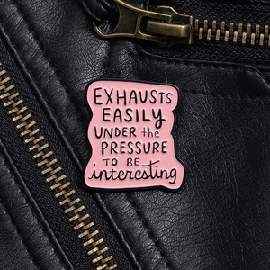 Nahaufnahme der rosa Emaille-Anstecknadel auf schwarzer Lederjacke mit Goldreißverschluss
