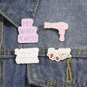 Set of four fun enamel pins with slogan designs on a blue denim jacket background