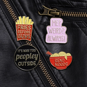Detail of cartoon enamel pins with fries and ramen shapes on a black leather jacket