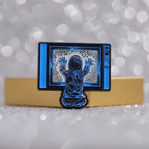 Enamel pin featuring a girl touching a blue vintage TV with static screen effect