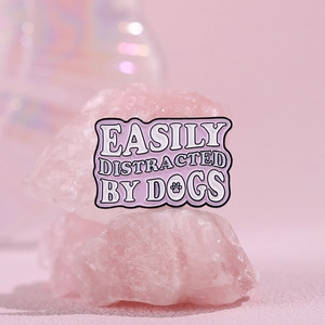 Macro detail of a pink enamel dog badge with Easily Distracted by Dogs text and paw print