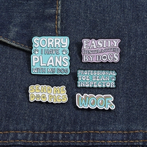 Set of five colorful dog enamel pins on denim fabric featuring cute pet phrases