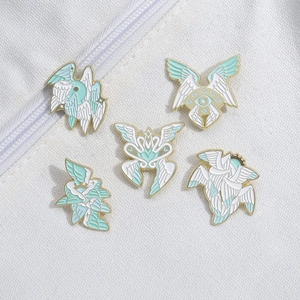 Set of five Seraphim enamel pins with wings and heart design on white fabric