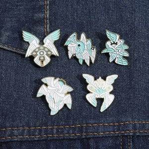 Macro detail of white feather wing and eye enamel pins on blue denim fabric background