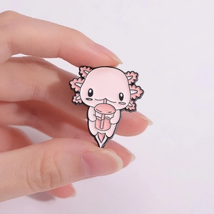 Cute pink axolotl enamel pin badge held in hand showing round edges and cartoon style