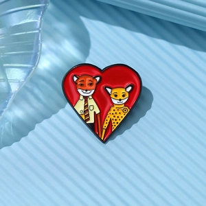 Cartoon fox and leopard enamel heart brooch pin on light blue textured background