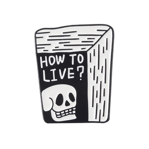 Détail macro du pin's en émail en forme de livre avec crâne et texte 'HOW TO LIVE?'