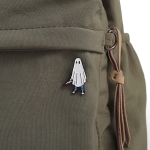 Détail d'un pin's fantôme en émail avec dague sur un sac à dos en toile vert armée