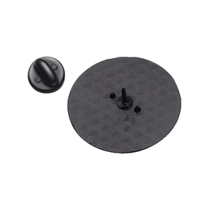 Detail of round black badge pin back featuring geometric embossed pattern and rubber clutch