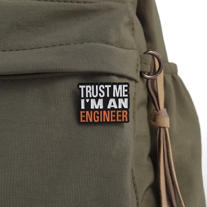 Trust Me I'm An Engineer enamel pin badge on olive green backpack strap