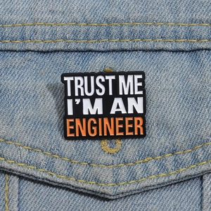 Macro shot of Trust Me I'm An Engineer enamel pin on a denim jacket pocket