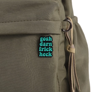 Detailed macro view of an enamel brooch with green artistic text on a woven fabric
