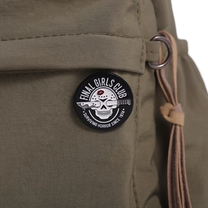 Macro shot of punk style Final Girls Club enamel pin on army green canvas jacket