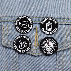Set of four black enamel pins with punk style graphics on a denim jacket pocket