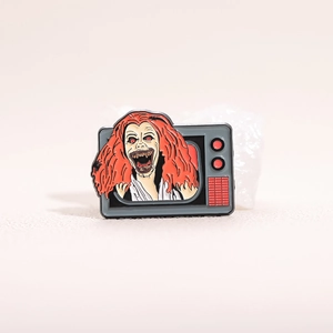 Creepy red-haired devil crawling out of vintage TV enamel pin with metallic finish