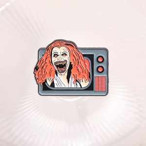Retro TV enamel pin featuring an orange-haired horror movie character on a white background