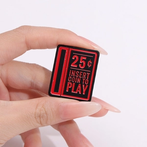 Macro shot of retro arcade enamel pin with red insert coin to play design and 25c text