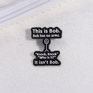 Close-up of This is Bob funny cartoon stickman enamel pin on white canvas background