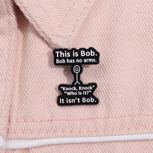 Close-up of a black enamel Bob stickman pin attached to pink denim fabric texture