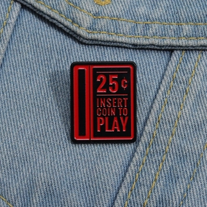 Retro arcade insert coin enamel pin on denim jacket with red and black text